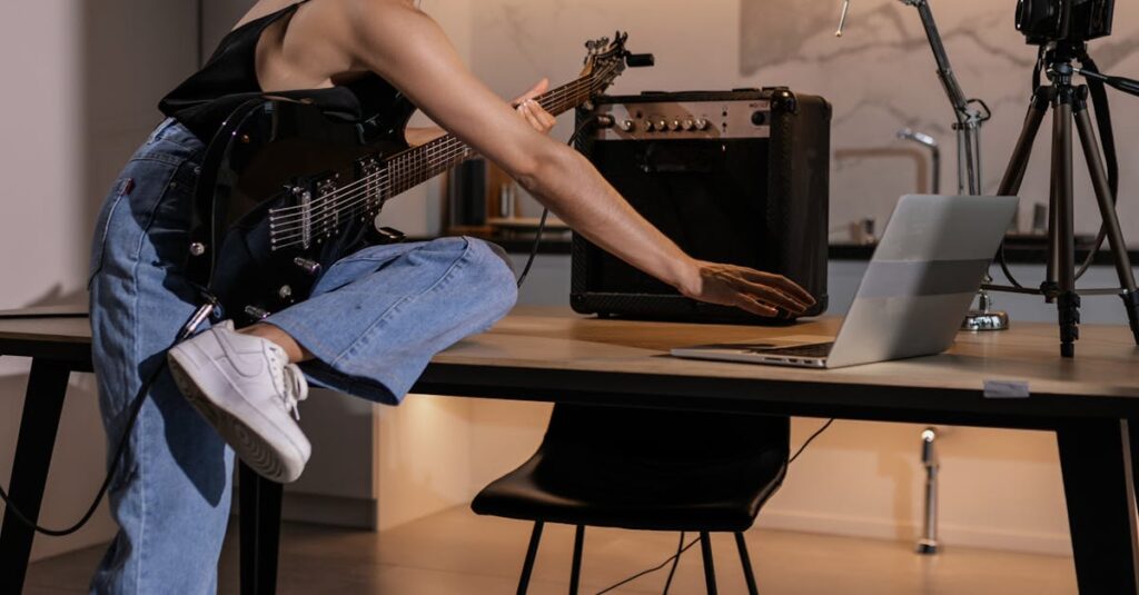 A young woman in a stylish setting learns guitar online using a laptop.